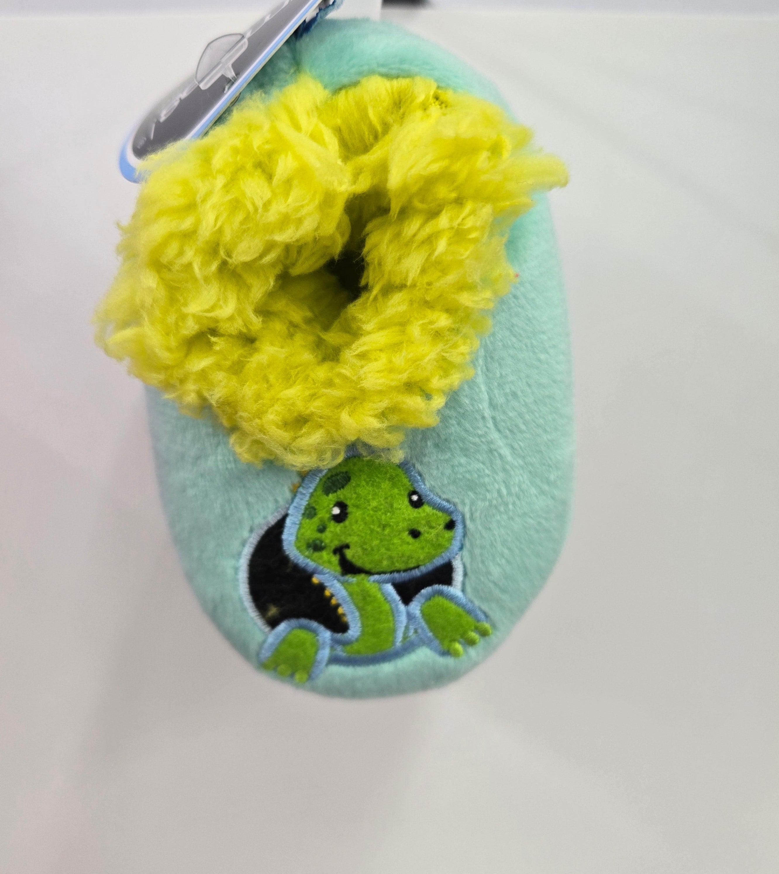 Plush slippers with a green dinosaur design on a white surface
